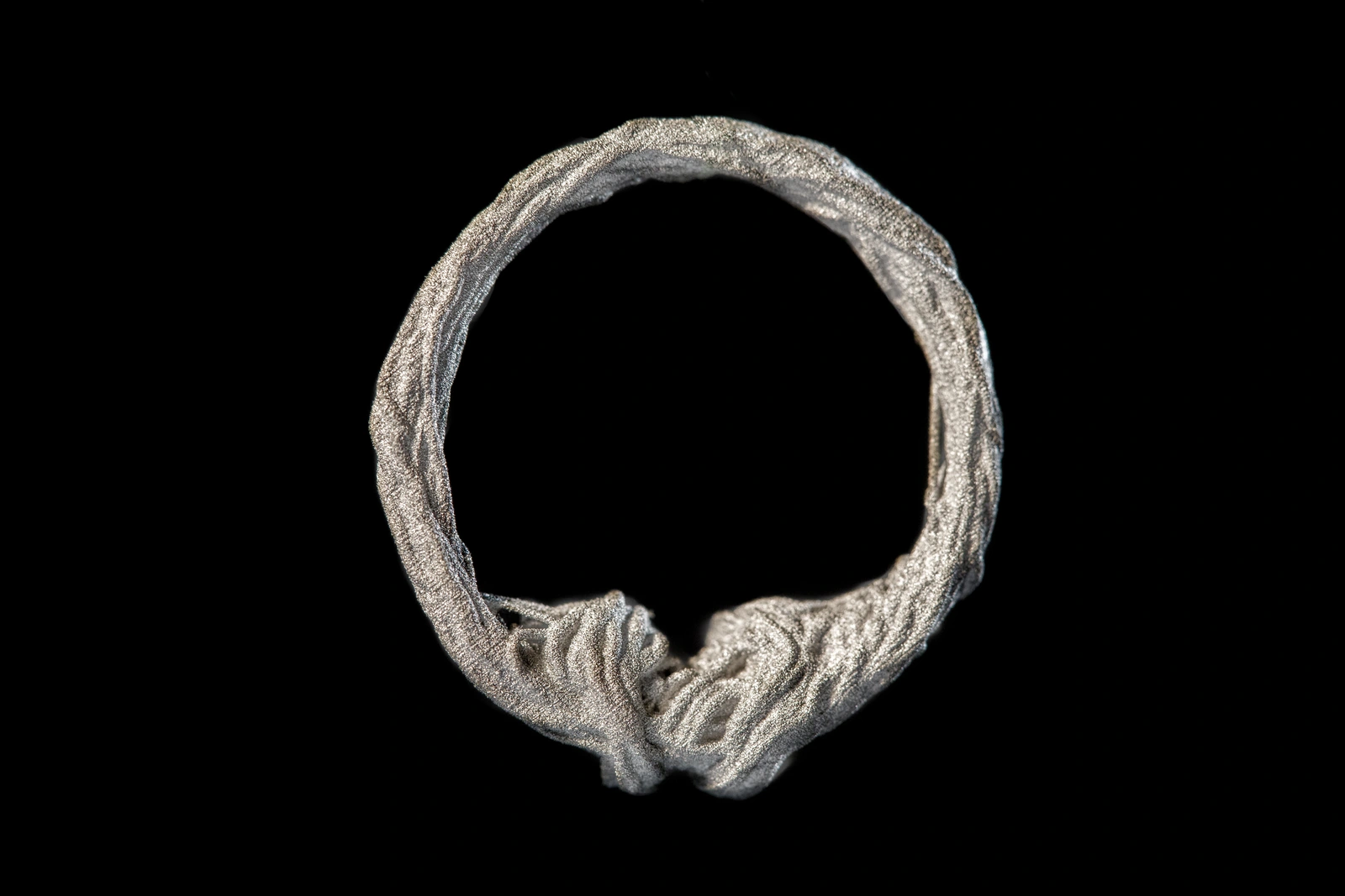 Metal ring from the Misbehaved jewellery project on a black background.