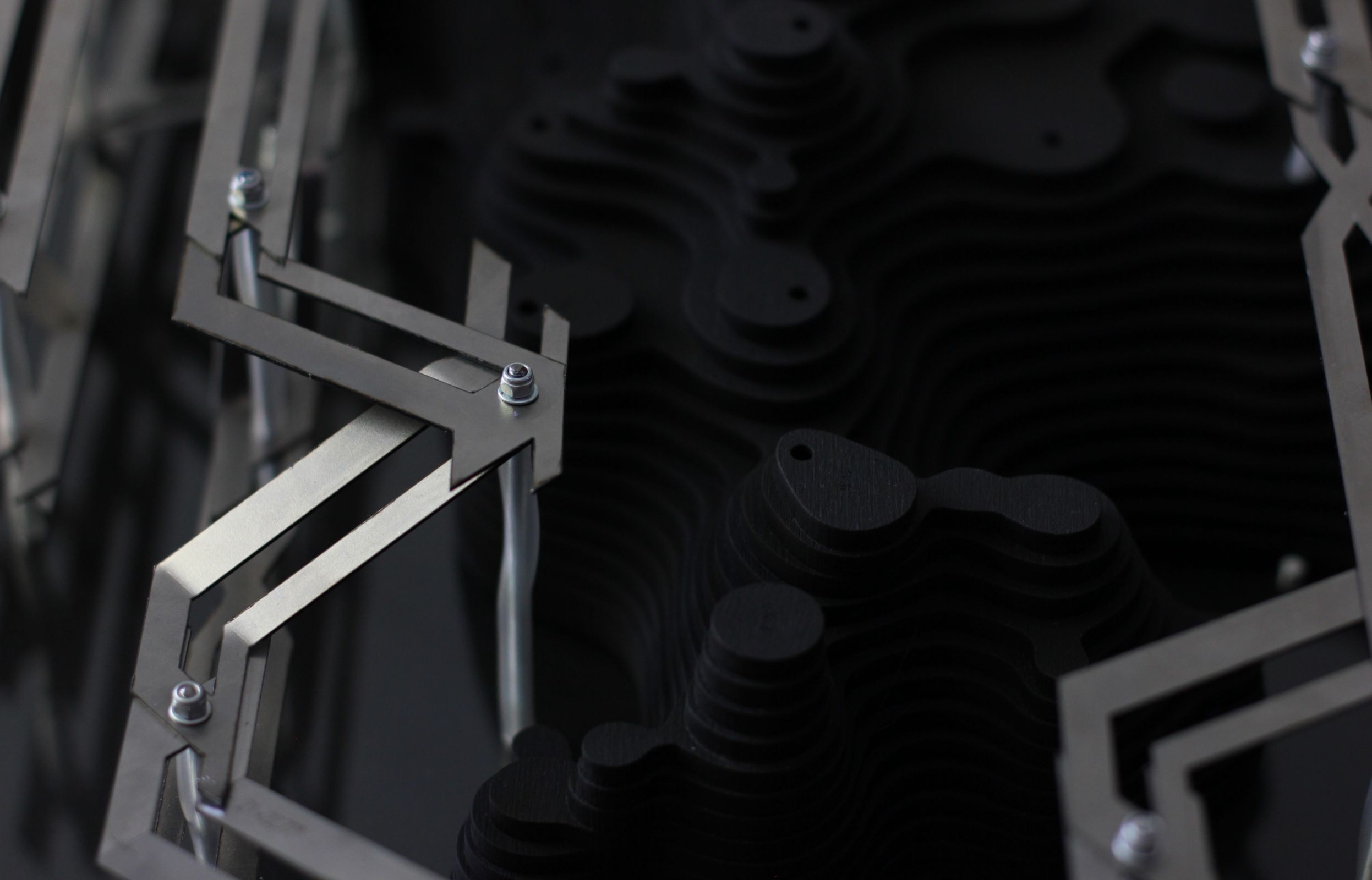 Close-up of fabricated model showing metal framework modules alongside dark layered wood components